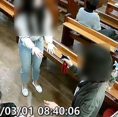 牧师夫人拿喷壶,给教徒手部消毒。