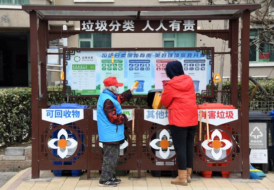 在北京市海淀区北平静庄街道金晖远洋社区,本年83岁的邰玉珍(左)引导社区住民倒垃圾(2021年3月5日摄)。邰玉珍是一名有着65年党龄的共产党员,退休后,她努力介入社区自愿办事。新华社记者 任超 摄
