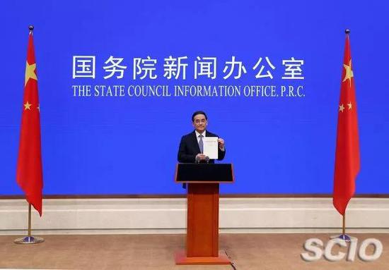 ▲徐麟在《新时代的中国与世界》白皮书发布活动上展示白皮书。(国新网 )