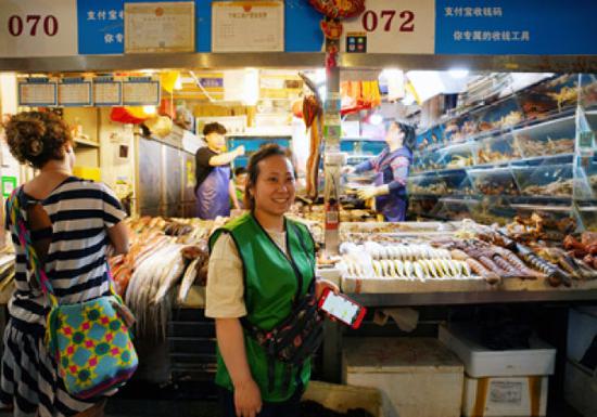 5月8日，在三源里市场，店主干丹君站在072号商铺前。