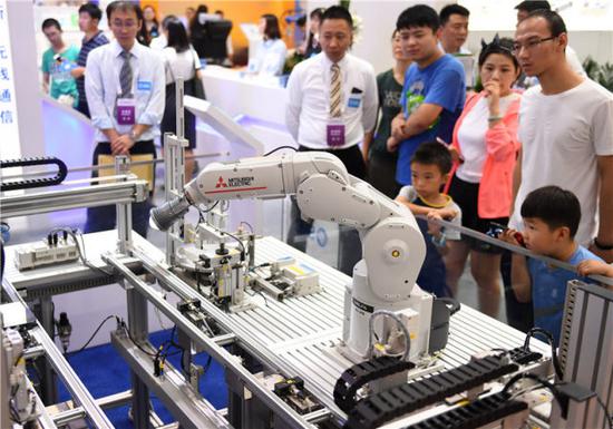 ↑观众在2018世界机器人大会上参观一款工业机器人（8月15日摄）。新华社记者 张晨霖 摄