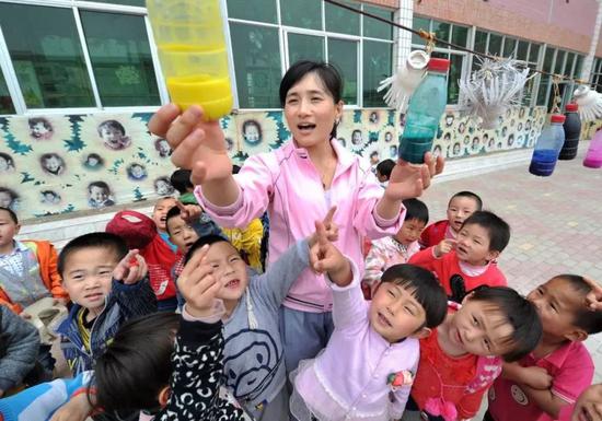  2013年6月5日，宁夏回族自治区西吉县幼儿园内，老师把小朋友们利用废旧瓶罐制作的装饰品挂在操场上。（新华社记者彭昭之 摄）