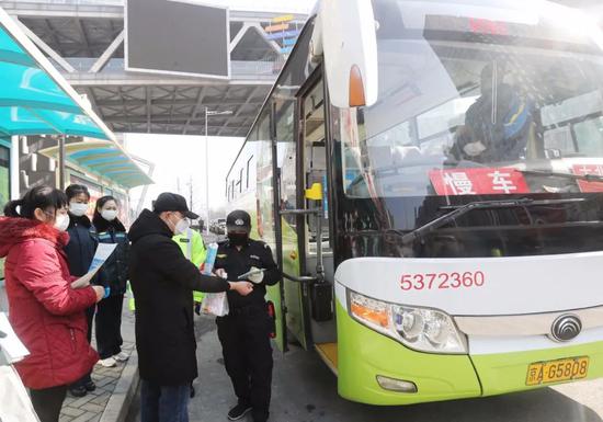 2020年2月10日,燕郊到北京郎家园818公交车,工作人员为乘客测量体温。新京报记者 王贵彬 摄