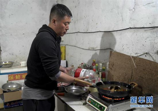 3月11日，古觉村驻村干部彭杨在做晚饭。 新华社记者 李力可 摄
