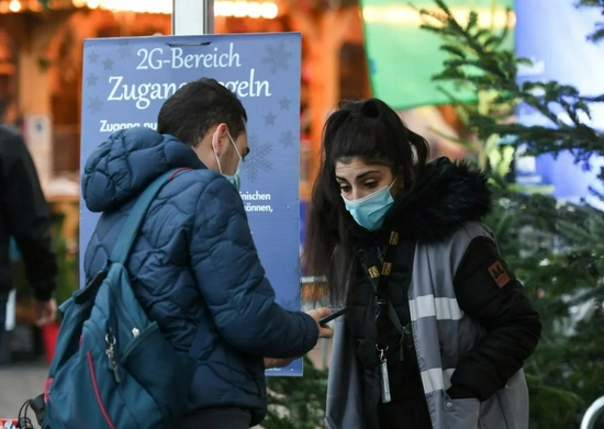 11月22日，在德国法兰克福圣诞市场外，一名工作人员检查市民的健康通行证。受新冠疫情影响，德国柏林、法兰克福等地的圣诞市场有的取消，有的在较为严格的防疫措施下开放。