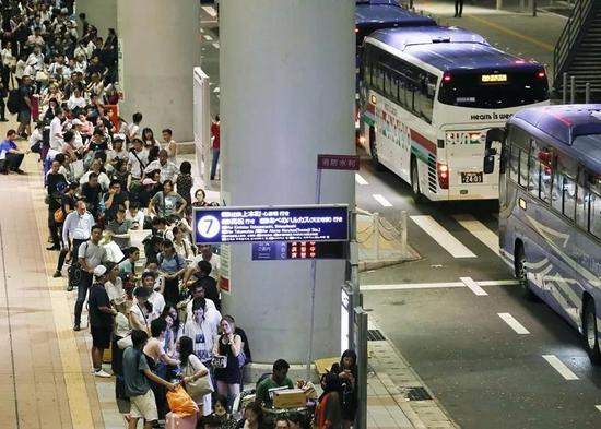 9月5日,在日本关西国际机场,旅客等候接驳巴士。新华社/共同社
