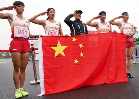 10月23日，中国队成员在女子个人全能越野跑比赛后手持国旗敬礼。