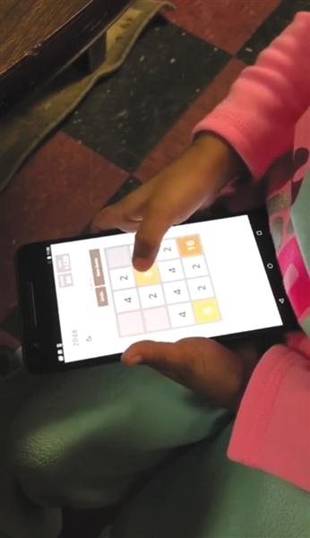 一名儿童正在安卓系统的智能手机上玩“2048”游戏，进行iCare软件的实验。受访者供图
