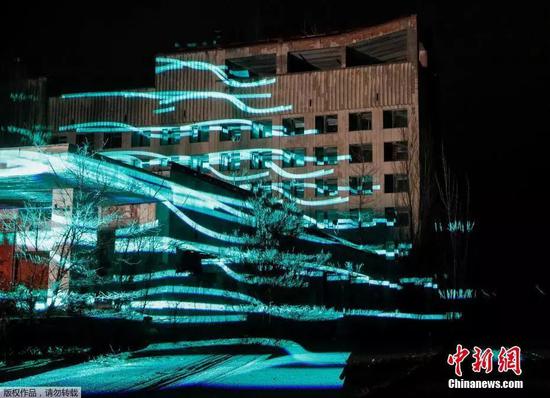 当地时间2018年11月22日,乌克兰普里皮亚季,参观者们在切尔诺贝利核电站附近观看一场“人工”数字雕塑的展示。