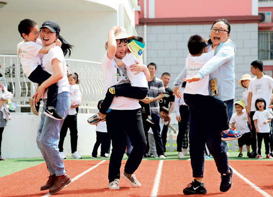 ▲ 5月30日,江苏省连云港市海州区一所幼儿园,家长与小朋友们一起进行亲子趣味游戏 王春摄 / 本刊