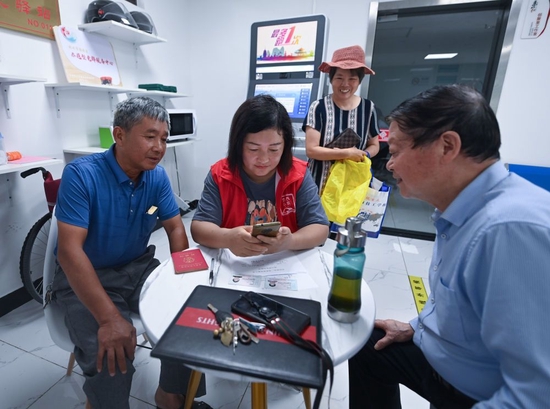 在杭州市临安区玲珑街道东山社区便民服务站,党员志愿者帮助居民填写公租房申请资料(2022年8月17日摄)。新华社记者 徐昱 摄