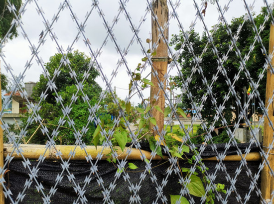  （图说：瑞丽边境一处已建成的防护网，透过网格缝隙，对面可见的建筑为缅甸一方的村庄房屋。图源人民网）