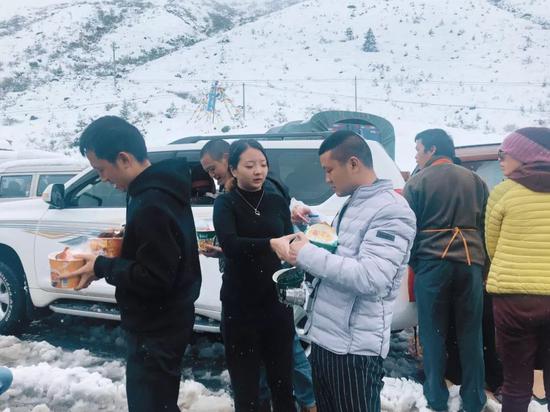 被困住的人们走出车，在雪地中吃泡面。受访者供图
