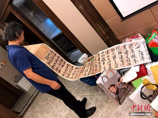 沈巍展示网友赠送的书法作品。廖雪芝 摄