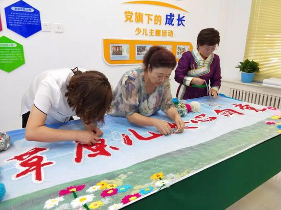  △社区的蒙古族、汉族同胞正在联手制作刺绣作品《草原儿女心向党》。（国广记者蔡靖骉拍摄）