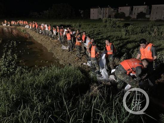 ▲7月15日晚,江西鄱阳油墩街镇东联圩发生管涌,火箭军部队官兵排起长龙,通过接力方式进行沙袋封堵作业。受访者供图