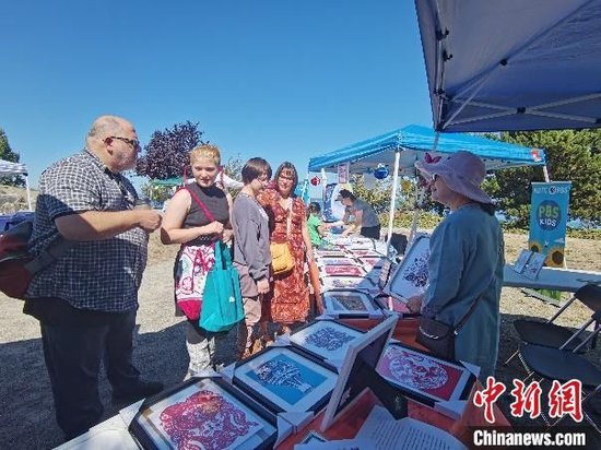 張麗麗在2023年美國塔科馬市中秋嘉年華活動中向當地民眾介紹中國剪紙。(受訪者 供圖)