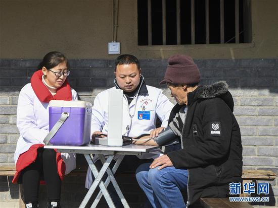 重庆市石柱土家族自治县中益乡卫生院的医护人员为华溪村村民谭登周测量血压(12月10日摄)。新华社记者 王全超 摄