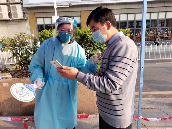 龙华街道三联社区党群服务中心社工黄爱华在核酸检测现场指导市民进行扫码。