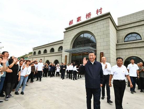 ↑这是14日下午，习近平在绥德县张家砭镇郝家桥村考察时，向乡亲们挥手致意。新华社记者 谢环驰 摄