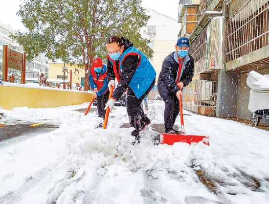  昨天清晨，顺义区胜利街道双兴南社区的工作人员正在清理积雪。本报记者 武亦彬摄
