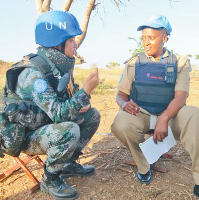 2017年11月29日，中国第四批赴南苏丹（朱巴）维和步兵营女兵班班长于培杰（左）在执行武器禁区巡逻任务休息期间，与共同执行任务的联合国警察交流心得体会。王理红摄