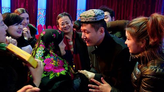 在2016北京电视台春节联欢晚会的演播厅内，古莱外尔老人为台主持人罗旭戴上了和田小花帽并送上自己的祝福。 千龙网记者 郑涛 摄