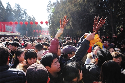 昨日，北京地坛庙会餐饮区，市民高举食物穿过人群。