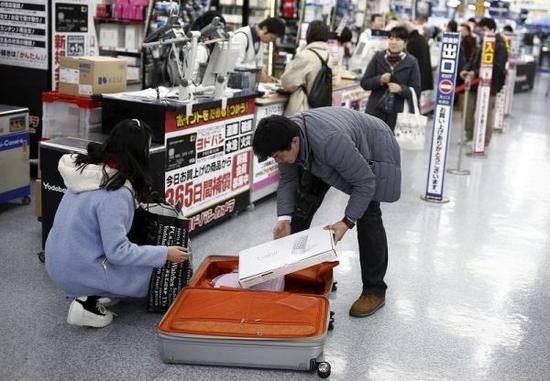 中国游客赴日“爆买”引发全国人大代表热议。图为中国游客在东京一家商场中购物后装箱。(路透社)