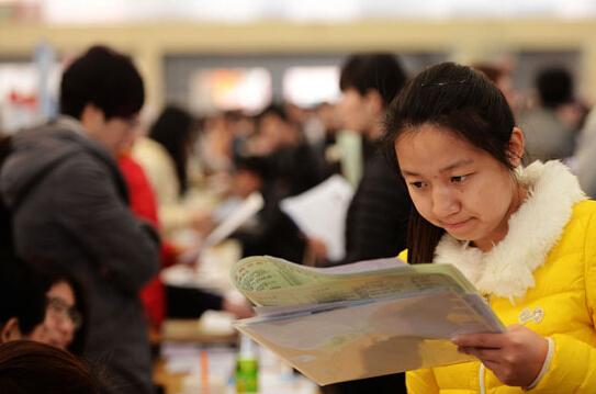 3月19日，山东省青岛市一高校招聘会现场，一名大学生在查看招聘企业资料。
俞方平/摄