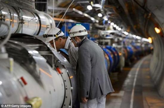 资料图：科学家注视着大型强子对撞机的一段环形隧道。