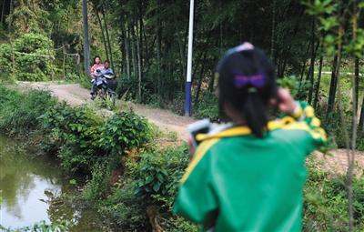 5月13日,湖南省长沙市宁乡县流沙河镇高山村,莎莎在家门口看着爷爷载姐姐回家,姐姐在寄宿初中上学,只有周末才能回家。