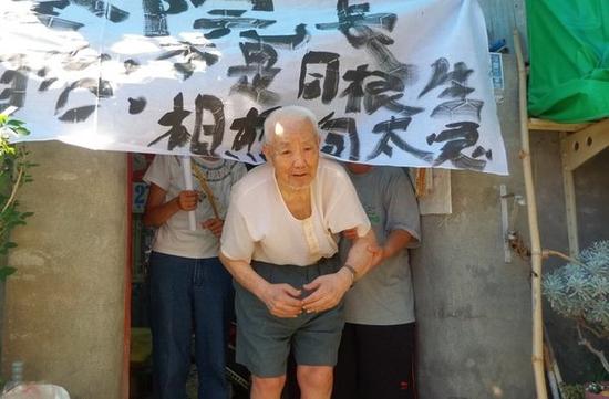　　遭强制搬迁的左营自治新村杨老先生，由家人牵到白布条下，请台湾新当局“救命”。（图片来源：台湾《联合报》）