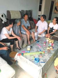 社区工作人员看望李明（左三）和他的母亲（左二）。社区供图