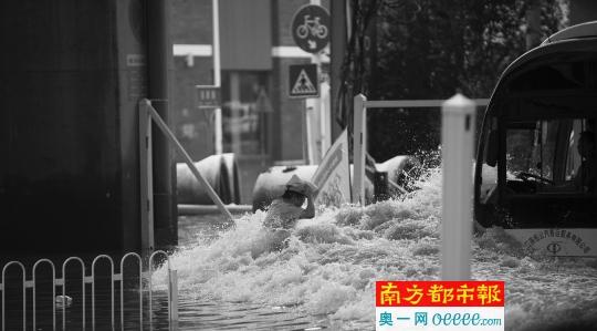 7日，一位武汉市民冒险从没过胸口的积水中通过，被一辆行经的公交车冲起的水浪冲击。