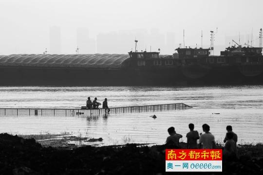7日傍晚，武汉长江干堤青山倒口湖段，救援人员连日奋战，处理了管涌险情，不少附近的市民来到堤上观察水位。