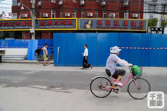 根据《2016年北京市缓解交通拥堵行动计划》，2016年北京市东城区需开工建设的道路有22条。图为7月14日一名市民正在骑车通过施工中的体育馆西路。千龙网实习记者 张曈摄