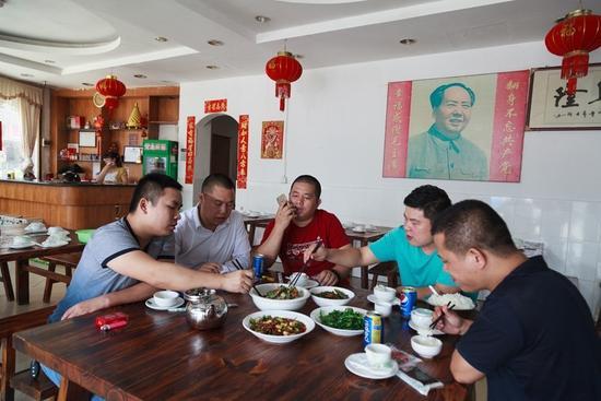 贺军与侄子在他开在大望村的餐馆里吃午饭（左一、左三、左四依次为贺背、贺军、贺熊）