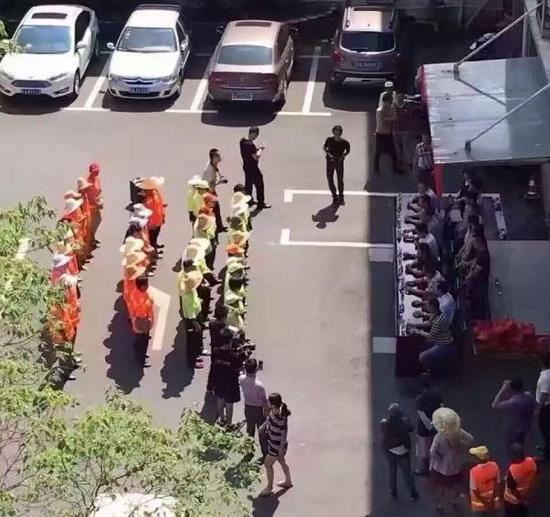 8月11日，江西南昌市青山湖区举行慰问环卫工人的爱心活动，图片中环卫工人站在烈日下，等待着坐在旁边阴凉处的领导们发放慰问品。微博 图