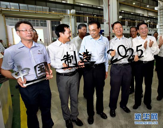 10月12日至13日，中共中央政治局常委、国务院总理李克强在广东深圳、东莞考察，并出席2016年全国大众创业万众创新活动周。这是10月13日，在深圳大族激光公司生产车间，工作人员拿着用激光切割而成的“中国制造2025”字样与李克强总理合影留念。 新华社记者 李涛摄