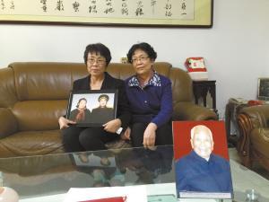 老将军的两个女儿捧着父母的照片。