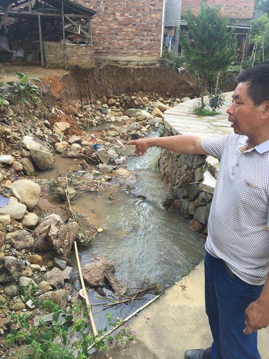 9月17日，站在周炳耀落水的地方，村民张华忠指着被水冲垮的河岸回忆险情。新华社记者 黄鹏飞 摄