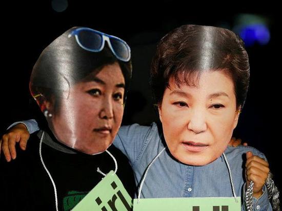 10月27日，韩国首都首尔市中心，抗议者戴着韩国总统朴槿惠（右）和其亲信崔顺实的头像站在一条街道旁。（新华/路透）
