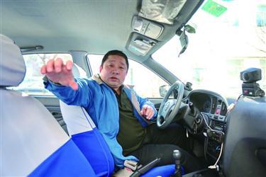 的哥郭师傅在车内向记者介绍当时与歹徒搏斗的经过。