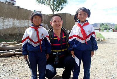 去日喀则偏远农村探访时，赵方印（中）给孩子发放完爱心款后，跟孩子们一起合影。