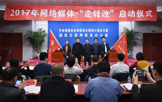 中央网信办副主任任贤良给参加网络媒体“走转改”活动的记者编辑代表授旗。(中国网信网 郭研 摄)
