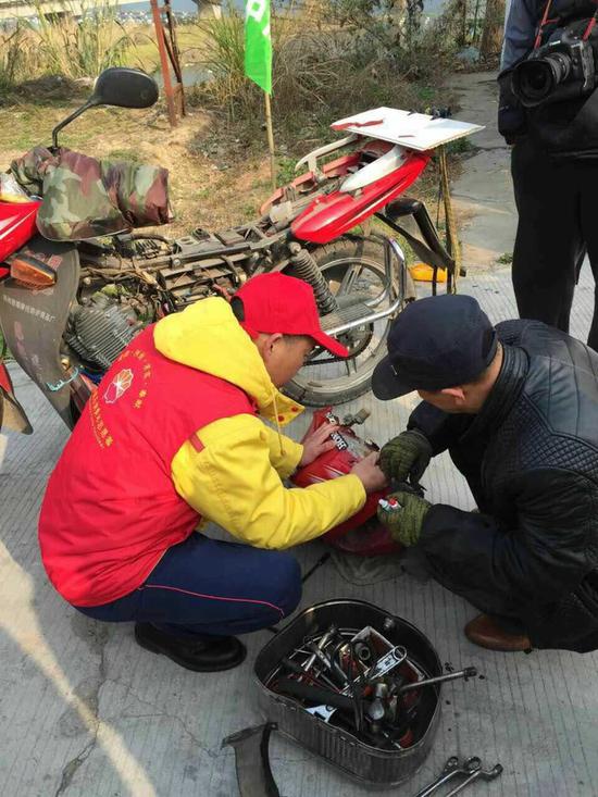     志愿者在修理返乡农民工的摩托车   
