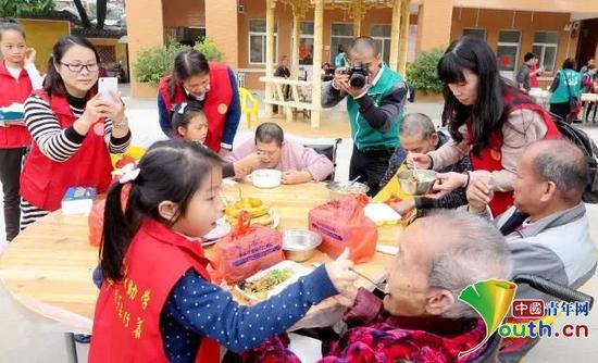 　　刘天明带领小榄中小学学生给敬老院老人们喂饭、敬老。本人供图