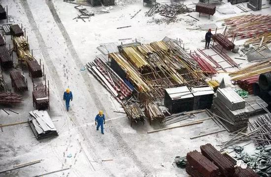 顶着雪在工地脚手架上忙碌的劳动者们。