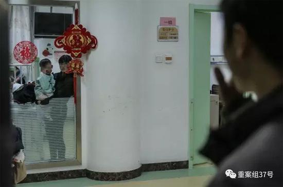 ▲2月21日晚,樊富贵的妻子抱着儿子站在病房窗前与丈夫相望。 新京报记者 彭子洋 摄